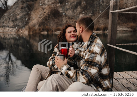 Couple shares warm drinks on a dock by a lake during a quiet moment together on Valentines Day 136366236