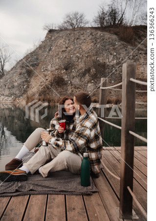 Couple enjoying time together by the water on Valentines Day while sharing drinks and moments of affection 136366243