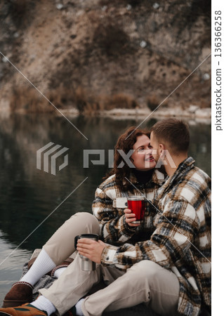 Couple enjoys time by the water on Valentines Day while holding warm drinks and sharing a moment together 136366258