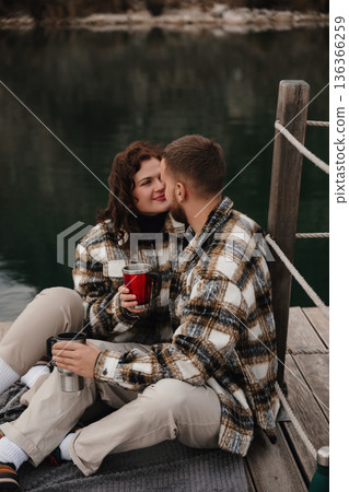 Couple enjoying a cozy moment together by the water on Valentines Day while sharing drinks 136366259