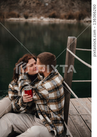 Couple enjoys quiet moment on dock with hot drink while celebrating love during winter season Couple enjoys quiet moment on dock with hot drink while celebrating love during winter season 136366260