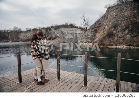 Couple embraces on wooden dock by the water during Valentines Day in winter month 136366265