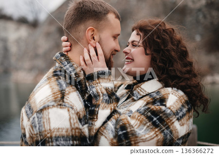 A couple sharing a moment together by the water on Valentines Day while wearing matching outfits in winter 136366272