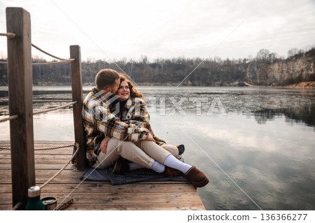 Couple sharing a quiet moment on lakeside deck during winter, celebrating romance and connection on Valentines Day 136366277