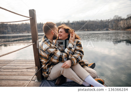 Couple sharing moments by the water on Valentines Day in cozy attire Couple sharing moments by the water on Valentines Day in cozy attire 136366284