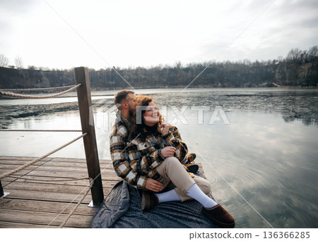 Couple enjoys quiet moment by the lake on Valentines Day while sitting together on a blanket 136366285