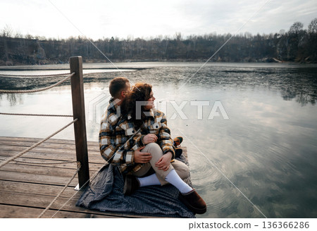 Couple enjoys a quiet moment by the water on Valentines Day, sharing their love at sunset in a cozy outdoor setting Couple enjoys a quiet moment by the water on Valentines Day, sharing their love at sunset in a cozy outdoor setting 136366286