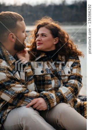 Couple sharing love on Valentines Day by the river in cozy outfits while enjoying their time together 136366292