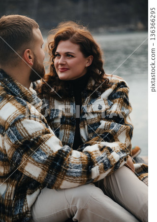 Couple enjoys each others company by the water on Valentines Day in cozy outfits, sharing moments of love and joy 136366295