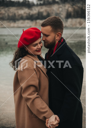 Couple enjoying a romantic moment together by the lake on Valentines Day with a cozy outfit in winter 136366312