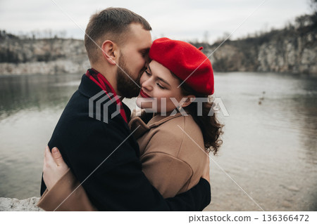 Couple sharing a moment by the lake on Valentines Day with a soft embrace and warm smiles 136366472