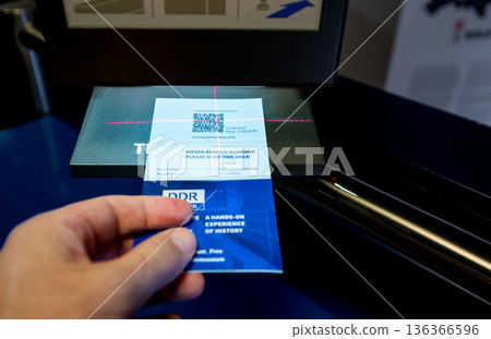 Berlin, germany, august 12, 2023. Person scanning a paper admission ticket with a qr code using a laser scanner for entry into the ddr museum in berlin Berlin, germany, august 12, 2023. Person scanning a paper admission ticket with a qr code using a laser scanner for entry into the ddr museum in berlin 136366596