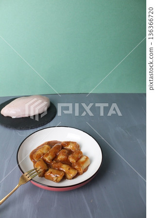Chicken sausages in tomato sauce next to chicken fillet on a gray background with space for the text of the Krpispeis. Chicken dishes. 136366720