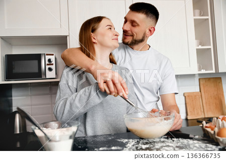 Couple enjoys cooking together in a modern kitchen while making a batter for a dessert during a weekend morning 136366735
