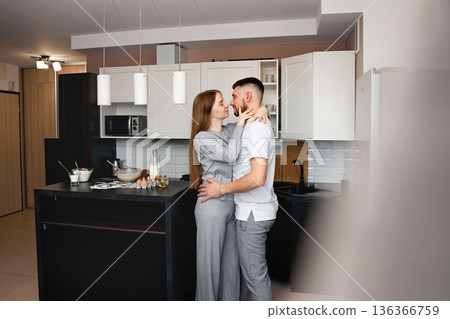 Couple shares a moment in kitchen while preparing food together in their modern home at daytime 136366759