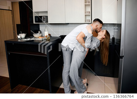 Couple enjoys a moment together in the kitchen during a cozy morning at home in a modern apartment setting Couple enjoys a moment together in the kitchen during a cozy morning at home in a modern apartment setting 136366764