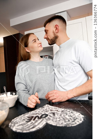 Couple enjoys cooking together in a kitchen while preparing a dessert at home during an afternoon Couple enjoys cooking together in a kitchen while preparing a dessert at home during an afternoon 136366774
