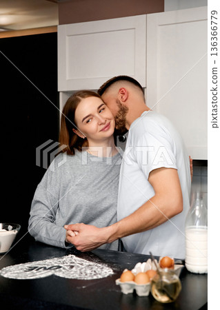 Couple in a kitchen share a moment while preparing breakfast in a cozy home setting during the morning hours 136366779