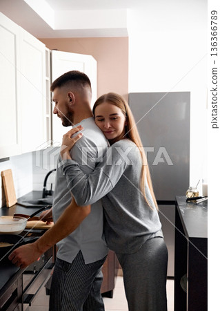Couple cooks together in a modern kitchen while sharing a moment of affection during the morning hours on a weekend 136366789