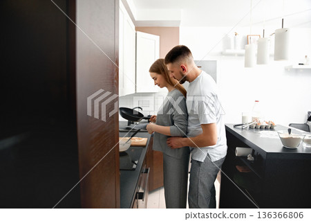 Couple cooking together in a modern kitchen during a weekend morning while sharing a warm moment of connection and love Couple cooking together in a modern kitchen during a weekend morning while sharing a warm moment of connection and love 136366806