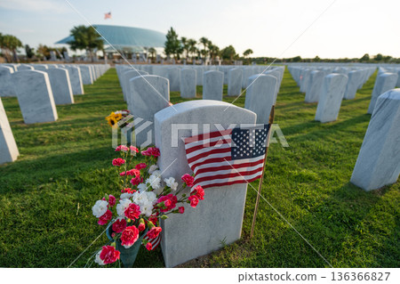 Sarasota National Cemetery with many white headstones with USA flags and flowers on green grass lawn. Memorial Day concept Sarasota National Cemetery with many white headstones with USA flags and flowers on green grass lawn. Memorial Day concept 136366827