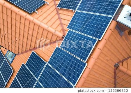Aerial top view of new modern residential house cottage with blue shiny solar photo voltaic panels system on roof. Renewable ecological green energy production concept. Aerial top view of new modern residential house cottage with blue shiny solar photo voltaic panels system on roof. Renewable ecological green energy production concept. 136366830