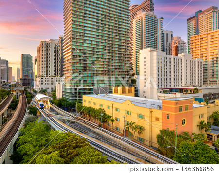 Aerial view of public train tracks running through the modern downtown of Miami, Florida, USA. High-rise buildings over railroad at golden hour 136366856