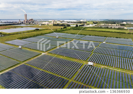 Modernization of power infrastructure at fossil fuel power plant. Solar photovoltaic panels illustrate the region move toward sustainable and renewable energy sources 136366930