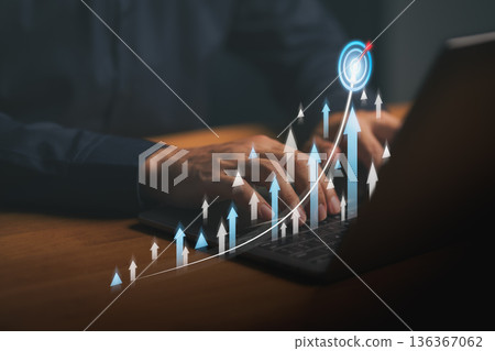 Hands typing on laptop keyboard with digital growth arrows and target icon, symbolizing business success, data analytics, online marketing performance, and financial progress concept. 136367062