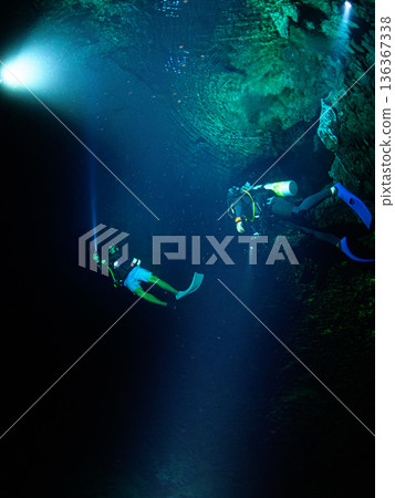 Divers swimming through underwater caves, Palau, diving scene 136367338