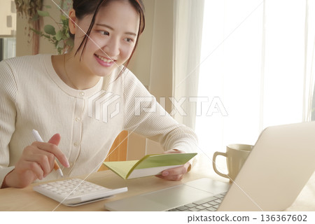 一位女士正在查看她的銀行存摺來管理她的錢。 一位女士正在查看她的銀行存摺來管理她的錢。 136367602