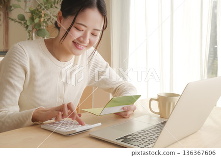 一位女士正在查看她的銀行存摺來管理她的錢。 136367606