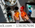Top view of the hands arranging dye jars for easter egg coloring on sunlit table. 136367696