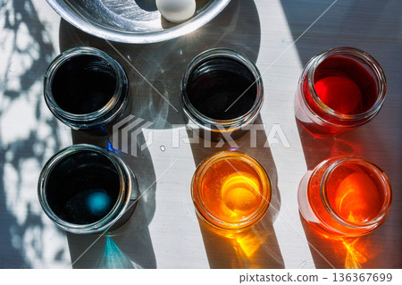 Top view of colorful food dye glass jars for easter egg dyeing in sunlight 136367699