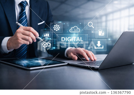 AI generated businessman using tablet and laptop with holographic interface icons for digital transformation cloud data analytics fintech and enterprise technology 136367790