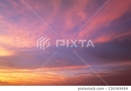Colorful sunset sky with setting sun behind vivid orange and yellow clouds Colorful sunset sky with setting sun behind vivid orange and yellow clouds 136369484