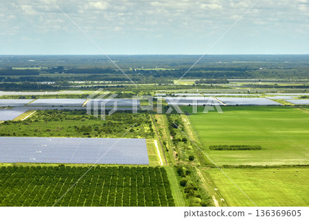Aerial view of sustainable electrical power plant between agricultural farmlands with photovoltaic panels for producing clean electric energy. Concept of renewable electricity with zero emission 136369605