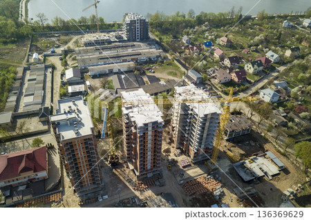 Apartment or office tall buildings under construction, top view. Tower cranes on city landscape background. Drone aerial photography. 136369629
