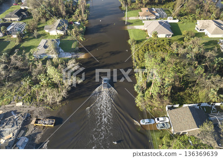 Flooded Florida road with evacuating cars and surrounded with water houses in suburban residential area. Consequences of hurricane natural disaster 136369639