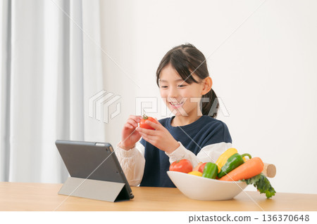 女孩拿著蔬菜，看著平板電腦 136370648