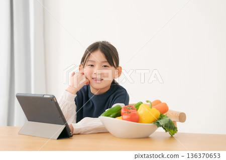 女孩拿著蔬菜，看著平板電腦 136370653