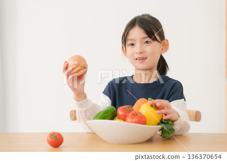 Girl holding vegetables while looking at tablet 136370654