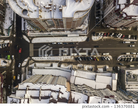 Aerial black and white winter top view of modern city with tall buildings, parked and moving cars along streets with road marking. Urban cityscape, view from above. Aerial black and white winter top view of modern city with tall buildings, parked and moving cars along streets with road marking. Urban cityscape, view from above. 136370881