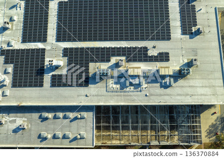 Production of sustainable energy. Aerial view of solar power plant with blue photovoltaic panels mounted on industrial building roof for producing green ecological electricity Production of sustainable energy. Aerial view of solar power plant with blue photovoltaic panels mounted on industrial building roof for producing green ecological electricity 136370884