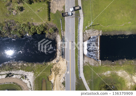 Damaged road bridge destroyed by river after flood water washed away asphalt. Rebuilding of ruined transportation infrastructure Damaged road bridge destroyed by river after flood water washed away asphalt. Rebuilding of ruined transportation infrastructure 136370909