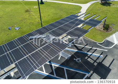 Destroyed by hurricane wind photovoltaic solar panels mounted on carport roof for producing green ecological electricity for electric vehicle charging. Consequences of natural disaster in Florida 136370918