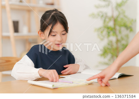 Elementary school girl being taught how to study 136371584