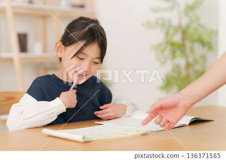 Elementary school girl being taught how to study Elementary school girl being taught how to study 136371585