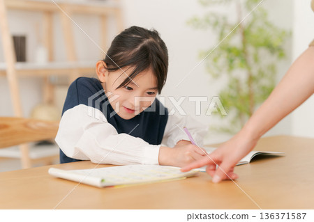 Elementary school girl being taught how to study Elementary school girl being taught how to study 136371587