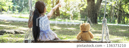 Banner Happy Child hug teddy bear in green park playground. Teddy bear best friend for little girl. Autism happy playing together on playground in happiness family feel love warm hugs with copy space 136373210